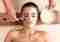 Professional beautician applying a facial mask to a woman in a spa.